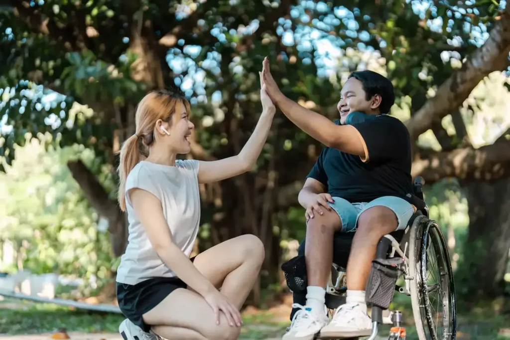 Support worker and disabled man in wheelchair doing a high five