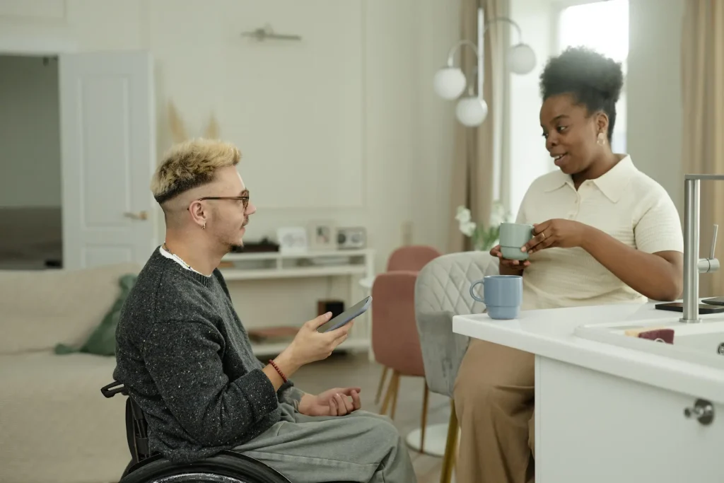 Man in wheelchair talking to support worker in kitchen