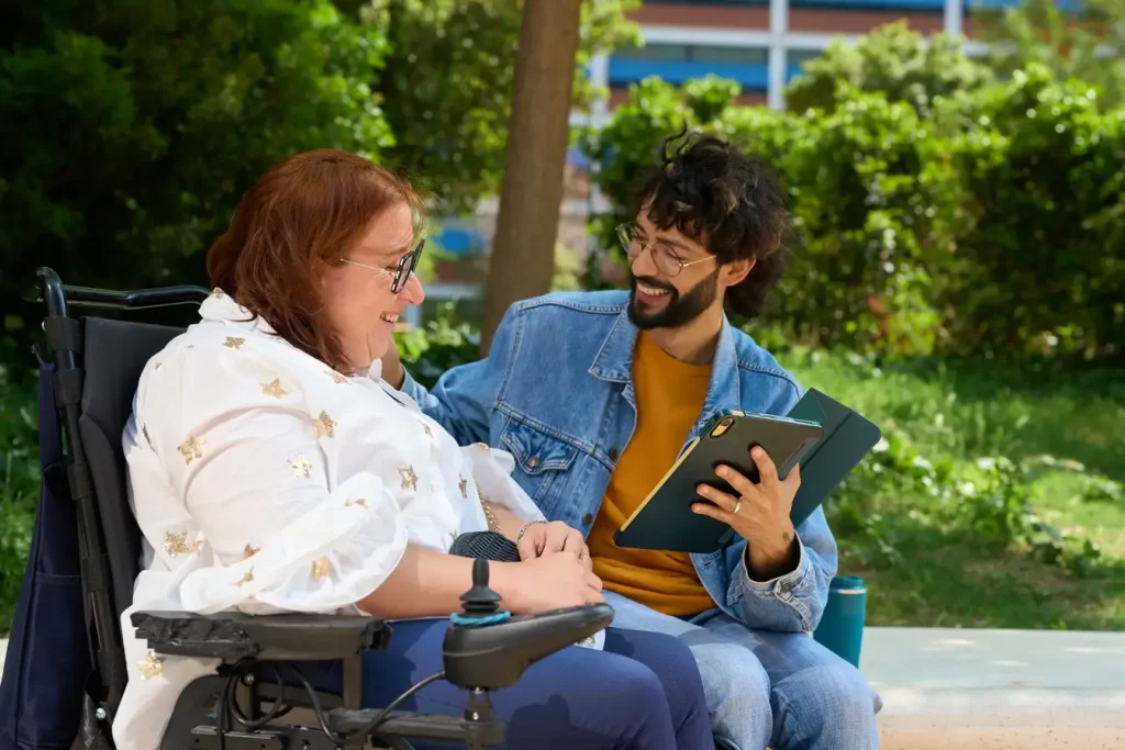 Support worker and disabled woman laughing while looking at tablet