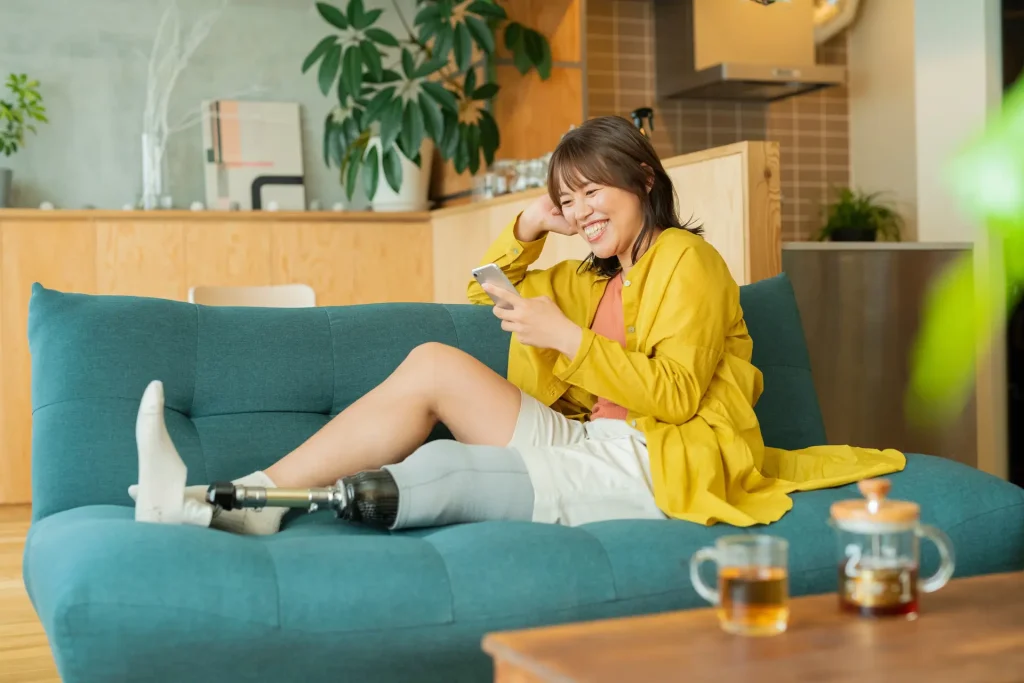 Disabled woman sitting on lounge smiling looking at phone