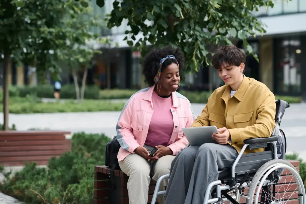 Man in wheelchair showing support worker something on a tablet